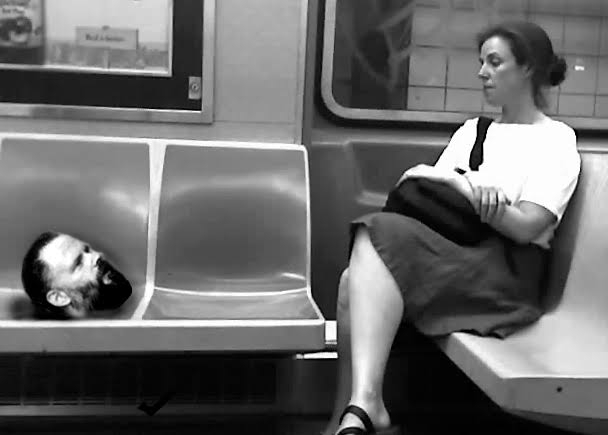 Philip Dick's head looking at a woman on a subway
